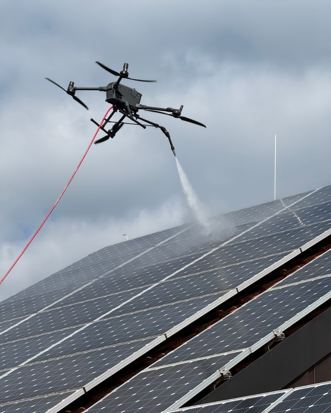 Drohne reinigt Solarmodule einer PV-Anlage mit Wasserstrahl